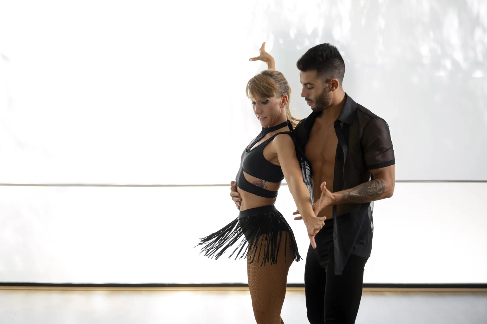 Dance instructor guiding a partner through a Latin move in a bright US studio