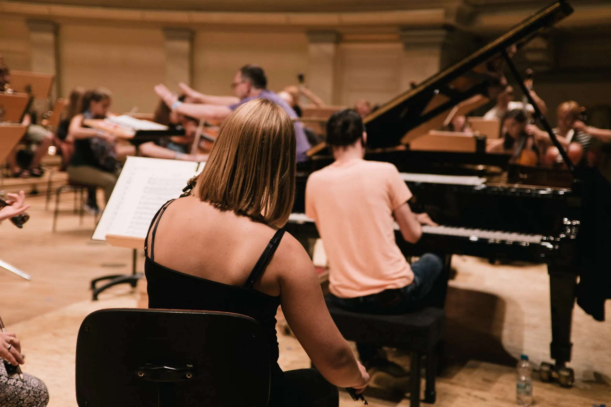 Orchestra pianist at a grand piano during rehearsal with strings section