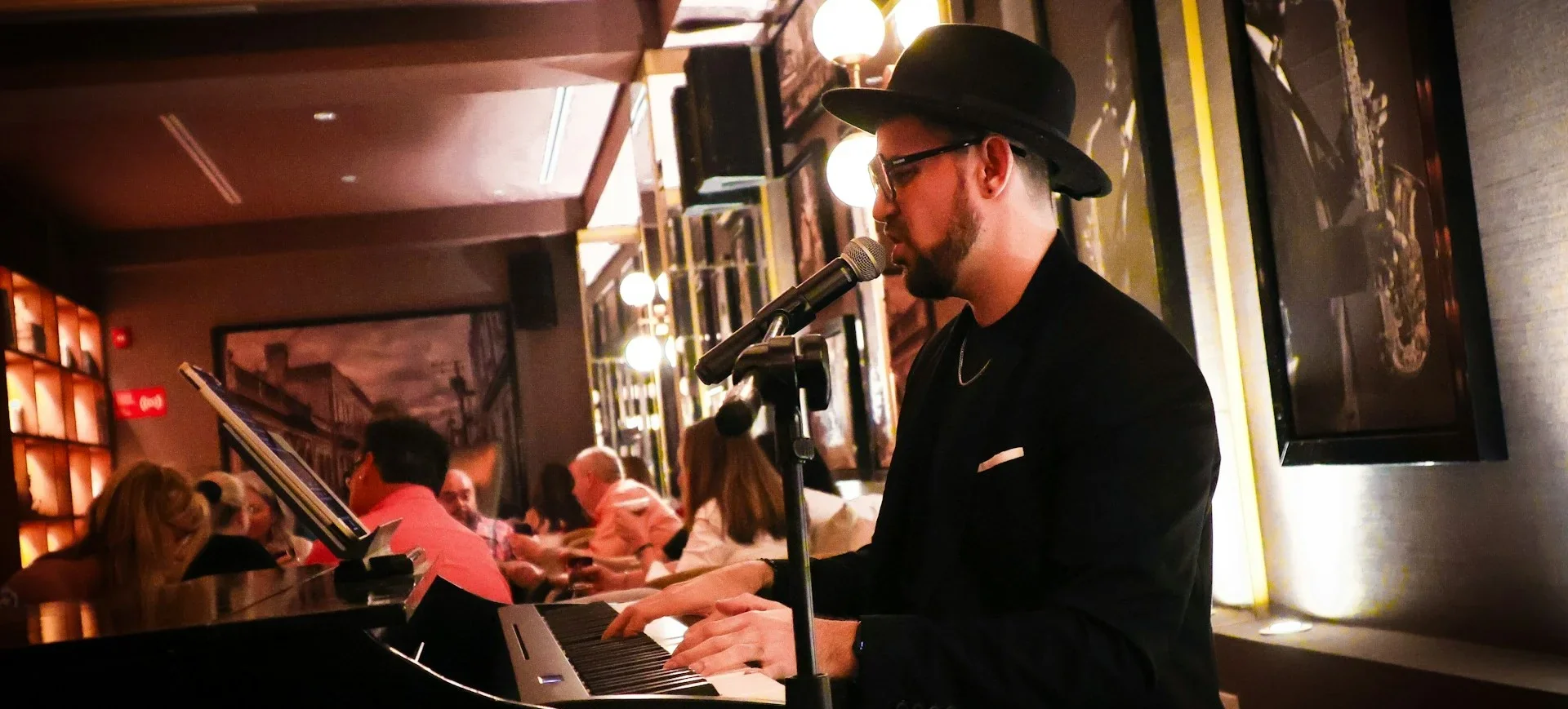 Lounge musician singing at a keyboard for guests in a dimly lit bar