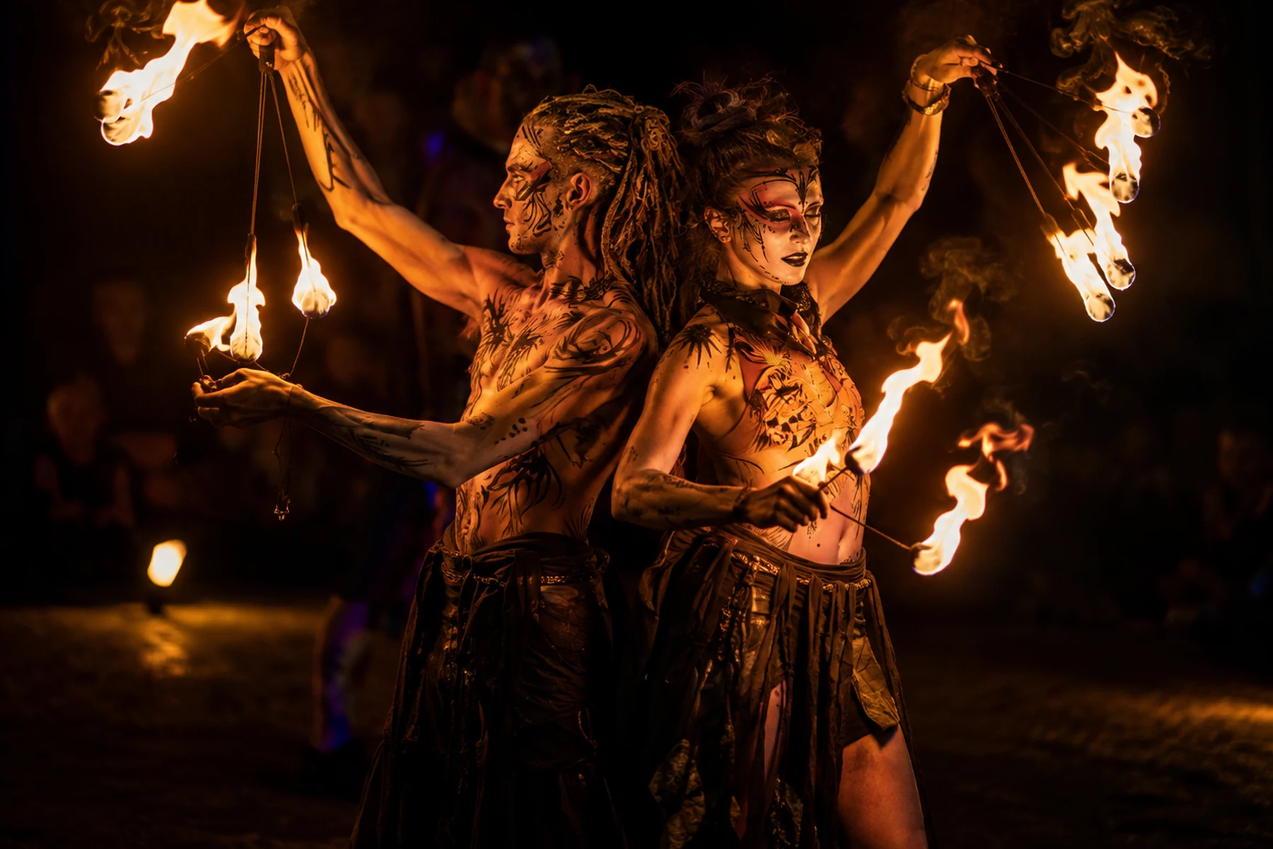 Fire show duo performing back to back with flaming props at night