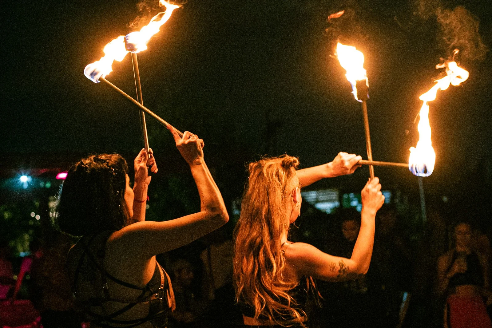 Fire show duo holding flaming torches during a night outdoor performance
