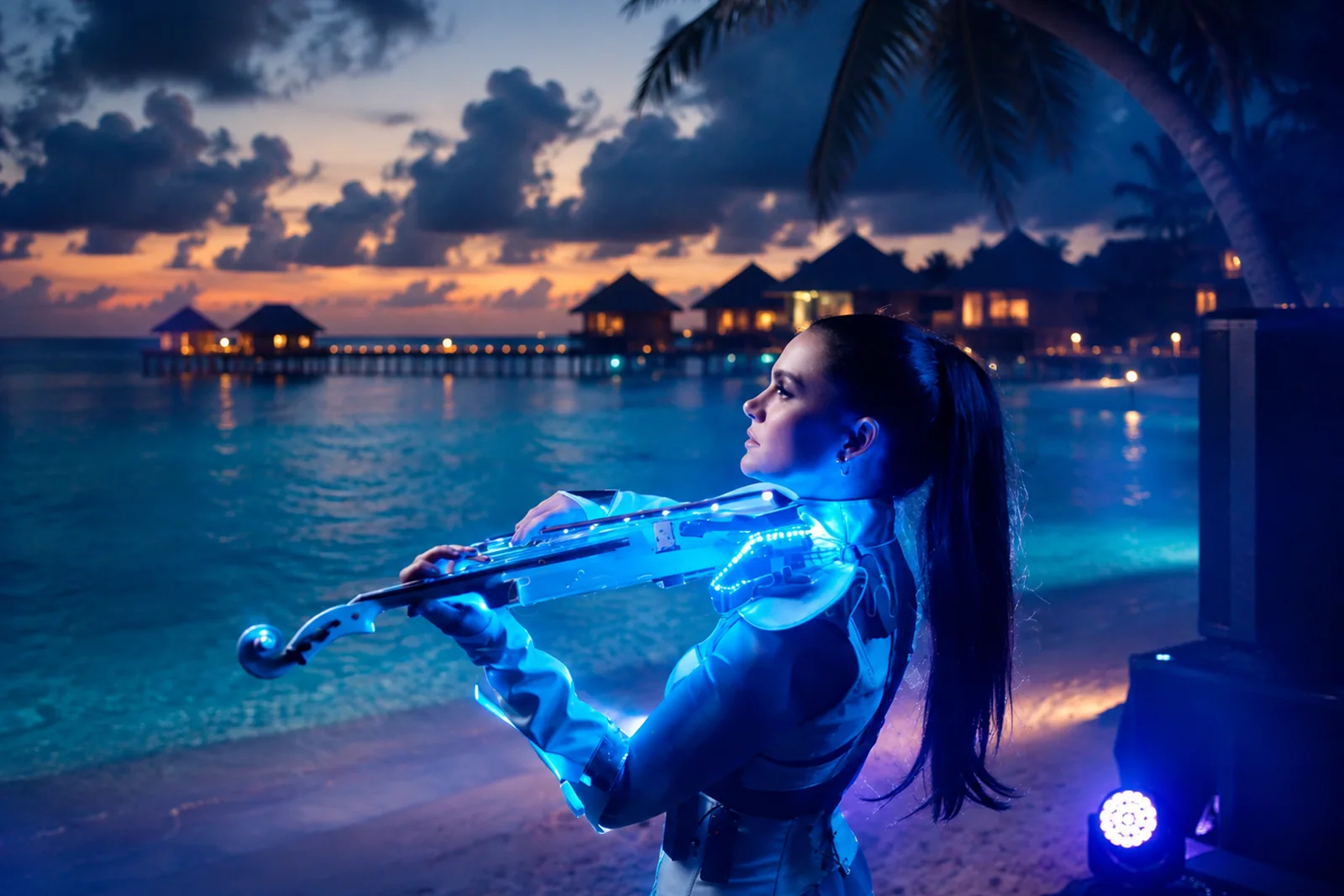 Electric violinist performing on a Maldives beach at twilight